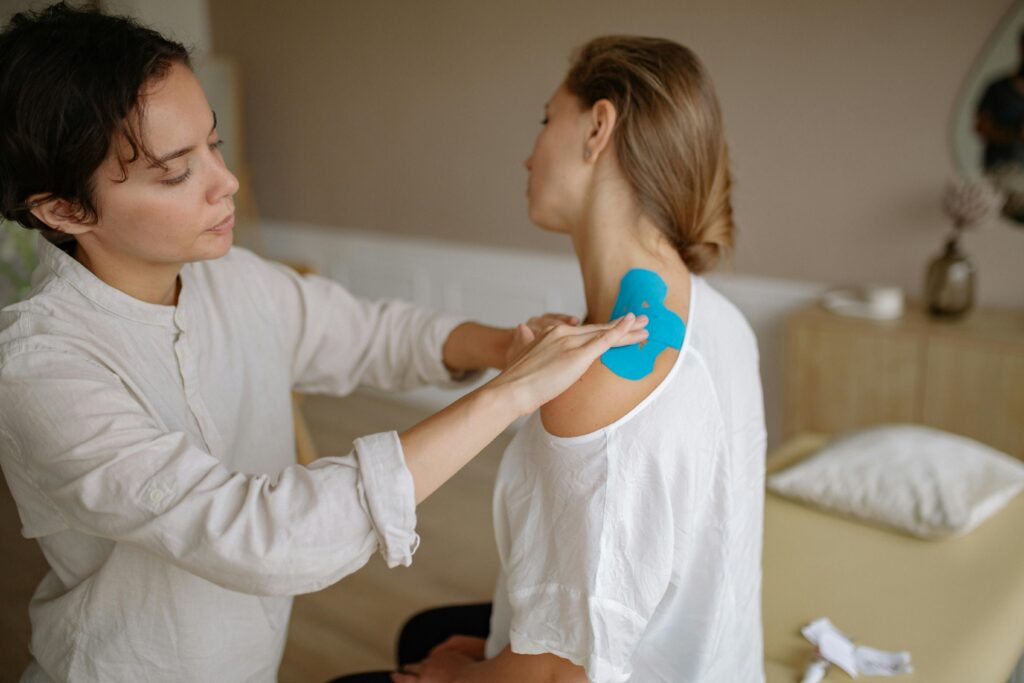 Woman having her shoulder taped by a physical therapist