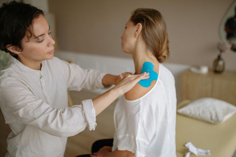 Woman having her shoulder taped by a physical therapist