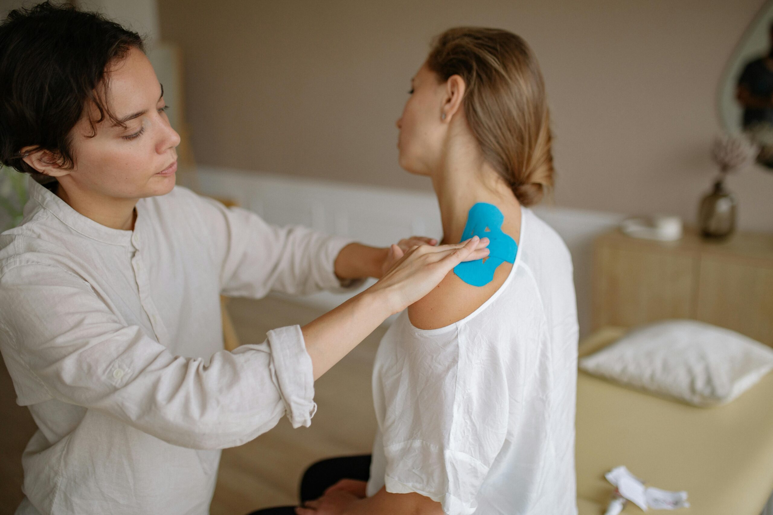 Woman having her shoulder taped by a physical therapist