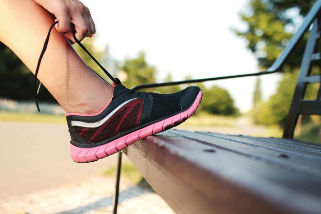Person tying their shoe on a bench
