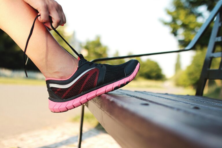 Person tying their shoe on a bench
