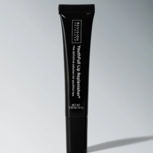 Black tube of Revision Skincare Youthful Lip Replenisher lip treatment standing upright on a light gray background, with product name visible.